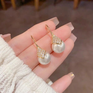 Detalle de pendientes de perlas de lujo con engaste de circón dorado en la mano