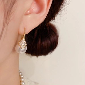 Primer plano de elegantes pendientes de perlas con circonitas en una modelo