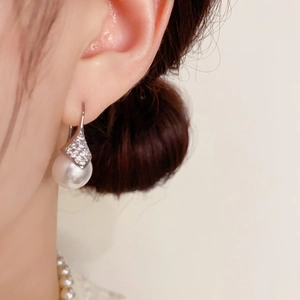 Elegante pendiente de perla con detalle de rombo con diamantes lucido por modelo