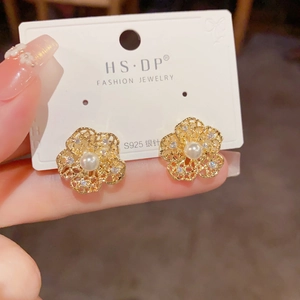 Detailed macro view of S925 silver golden flower earrings with pearl and rhinestones