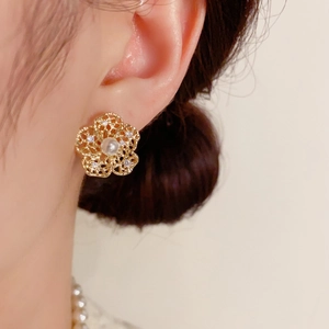 Close-up of golden hollow petal stud earrings with pearl and sparkling zircon accents