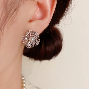 Elegant hollow floral stud earrings with silver metal petals and center pearl detail