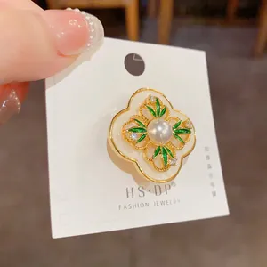 Detail of vintage four-leaf flower brooch with pearl and thick gold plating finish