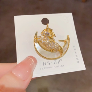 Détail d'une broche licorne avec strass et nacre blanche sur un croissant de lune doré