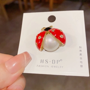 Detail of ladybug brooch with red enamel, white crystals and a large round pearl