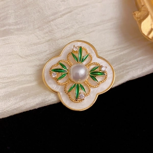 Elegant vintage clover brooch with green leaves and a large center pearl on white silk