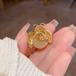 Golden ladybug beetle brooch pin with butterfly clutch back shown on hand