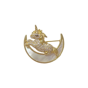Broche licorne dorée avec cristaux et incrustation de nacre sur un fond blanc pur