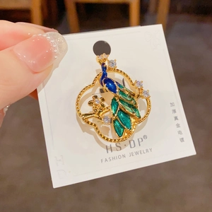 Exquisite gold-plated peacock brooch with blue enamel and sparkling white rhinestones