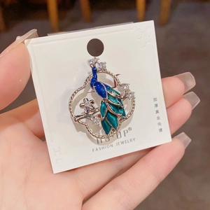 Detailed macro view of the silver peacock brooch with blue enamel and sparkling crystals
