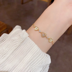 Elegant gold-plated heart bracelet with zircon and cat eye stone on a female wrist