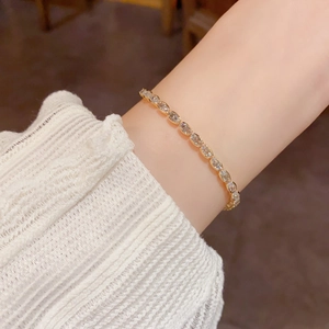 Close-up of elegant gold oval bracelet featuring sparkling zircon stones on a female wrist