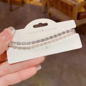 Detail of silver-tone tennis bracelet with marquise-cut rhinestones on display card