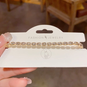 Detail of adjustable golden tennis bracelet featuring oval-cut clear cubic zirconia stones