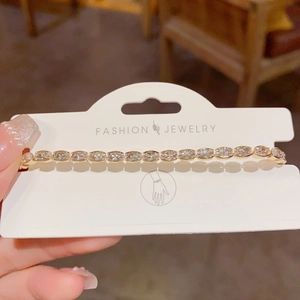 Detail of a gold-plated oval rhinestone bracelet with clear zircons on fashion card