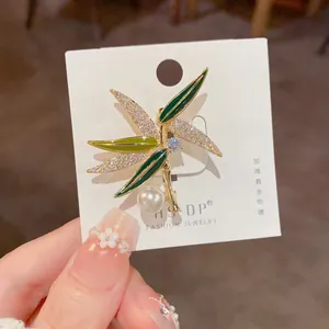 Détails d'une broche en bambou avec feuilles émaillées vertes, cristaux et perle