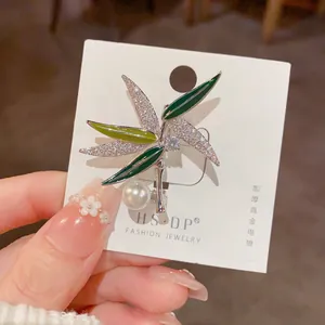 Détail de la broche bambou avec feuilles en émail vert, zircons et une grande perle blanche
