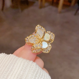 Macro d'une broche fleur dorée avec nacre iridescente et pierres de zircon cubique