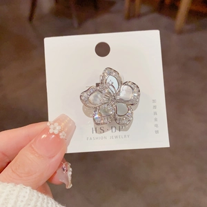Gros plan d'une bague fleur en zircon argenté sur carte avec décoration d'ongles