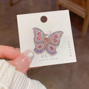 Macro shot of colorful zircon butterfly brooch with gold plating on a white jewelry card