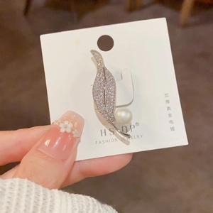 Detailed view of silver leaf brooch with micro-pave zircons and a large white pearl