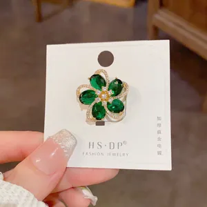 Detailed view of thick real gold plating flower brooch with green gems and zircons