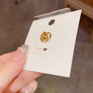 Detail of gold metal brooch clasp on white card holder held in hand for retail display