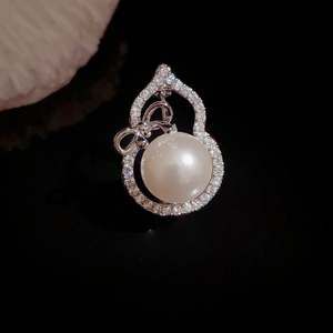 Exquisite hohle Flaschenkürbis-Brosche mit Perle und Schleifendetail auf schwarzem Grund