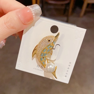 Detail view of gold-plated dolphin brooch with micro-pave zircons and white pearl