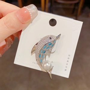 Macro detail of dolphin brooch with cubic zirconia, blue crystal fins and large pearl