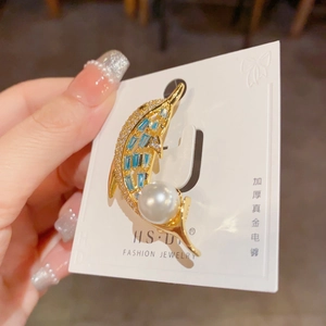 Detail of dolphin brooch with blue zircon, white pearl, and thick gold plating