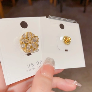 Eleganter goldener Blumenanstecker mit Mikro-Zirkonbesatz auf einer Schmuckkarte