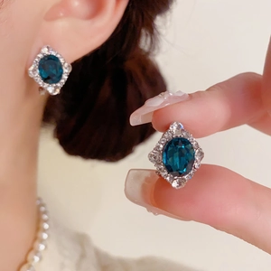 Gros plan de boucles d'oreilles saphir ovales vintage avec halo de zircons et monture argentée