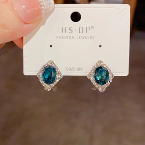 Gros plan détaillé des boucles d'oreilles losange avec cristal bleu et aiguilles en argent S925