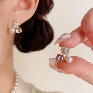Details eleganter goldener Ohrstecker mit Kristallkugel, Perle und lila quadratischem Stein
