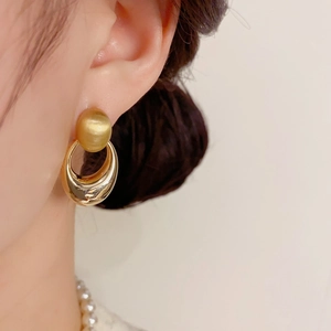 Nahaufnahme goldener geometrischer Ohrringe mit mattem Stecker und poliertem Ring