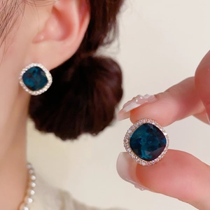 Gros plan de boucles d'oreilles carrées en cristal bleu marine avec un halo de zircon blanc