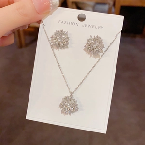 Macro detail of the sparkling flower necklace and pearl earrings set on display card