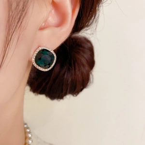 Gros plan de boucles d'oreilles carrées en émeraude et cristaux sur un modèle