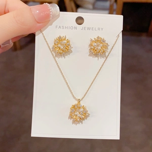 Detailed close-up of firework-style gold necklace and pearl earrings set on display card