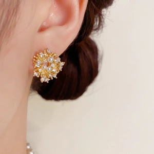 Detailed view of fireworks-inspired gold stud earrings with pearls and crystal inlay