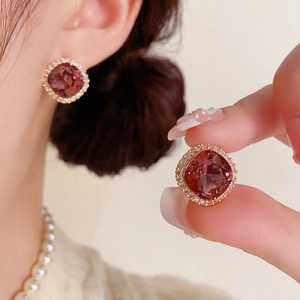 Gros plan sur des boucles d'oreilles carrées en rubis avec un halo de diamants scintillants