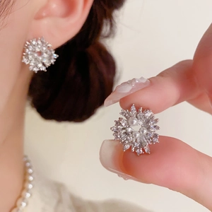 Close-up of snowflake stud earrings featuring sparkling crystals and center pearl detail