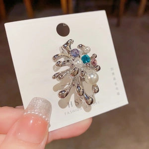 Détail de la broche en métal liquide argenté avec perles et strass multicolores