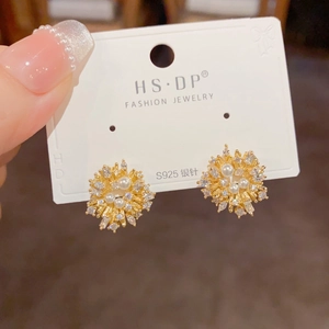 Macro detail of gold flower earrings featuring S925 silver needles and sparkling pearls