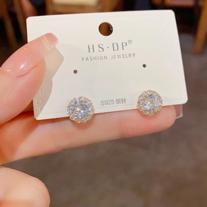 Gros plan de boucles d'oreilles fleur en argent et zircon avec pierre centrale et halo