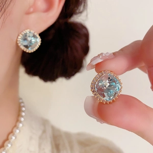 Gros plan de boucles d'oreilles bleu clair taille coussin et halo de zircons