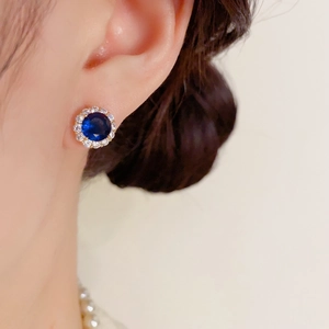 Gros plan sur une boucle d'oreille halo en zircon bleu avec collier de perles