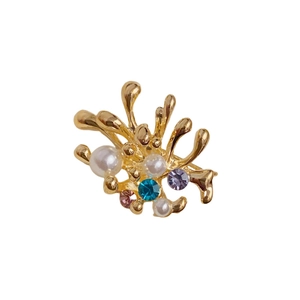 Broche feu d'artifice dorée avec perles et cristaux colorés sur fond blanc