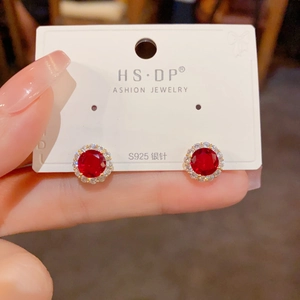 Détail macro de boucles d'oreilles rondes en zircon rouge et monture halo en argent S925